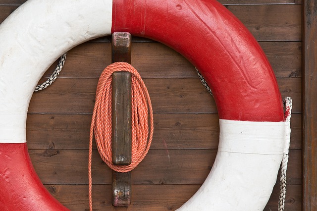 Red and white colored life preserver hanging on a wooden wall