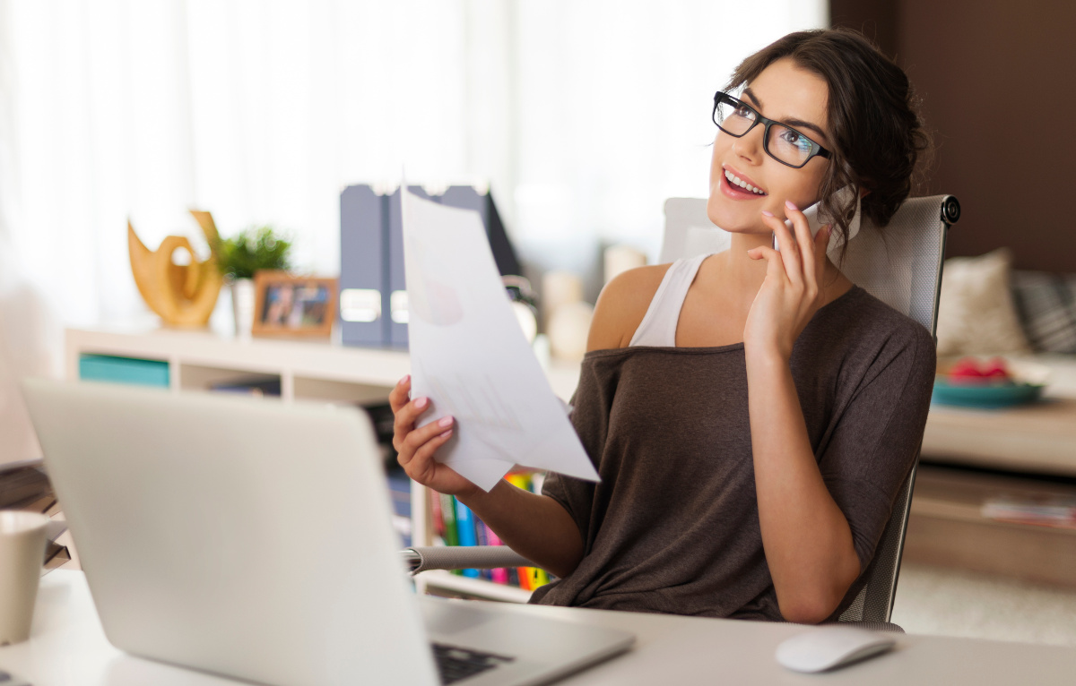 Young woman on cell phone working remotely from home office
