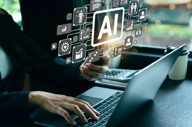A person types on a laptop, surrounded by digital icons related to AI technology. 