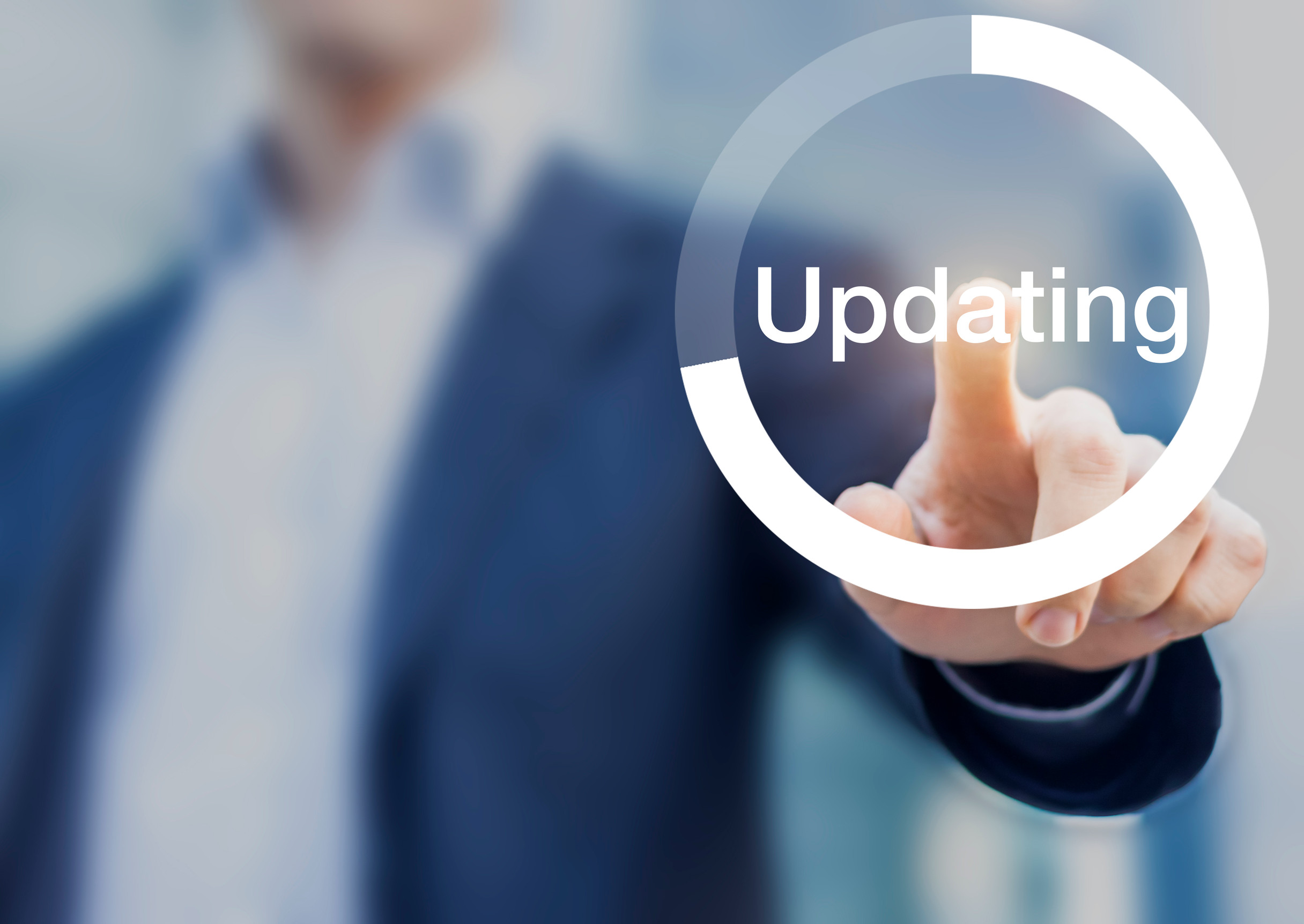 Close up of man pressing graphic of loading circle labeled 'Updating.'