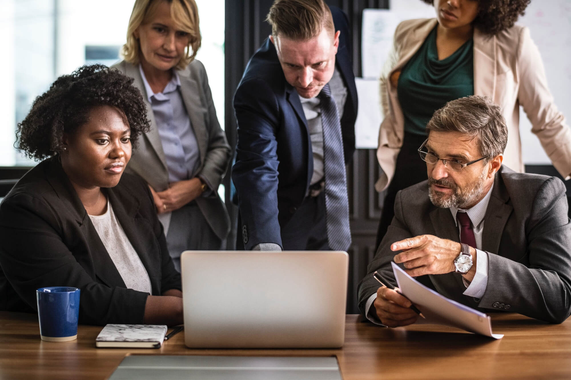 Group of 5 business professionals looking at a laptop