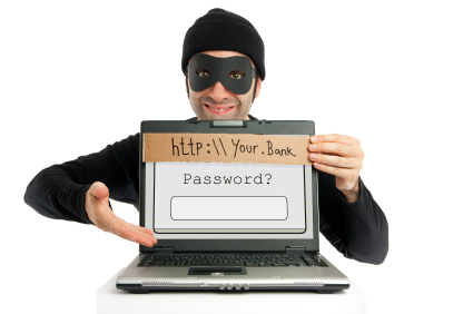 Masked criminal holding a cardboard sign that says 'http:\\Your.Bank' in front of a laptop