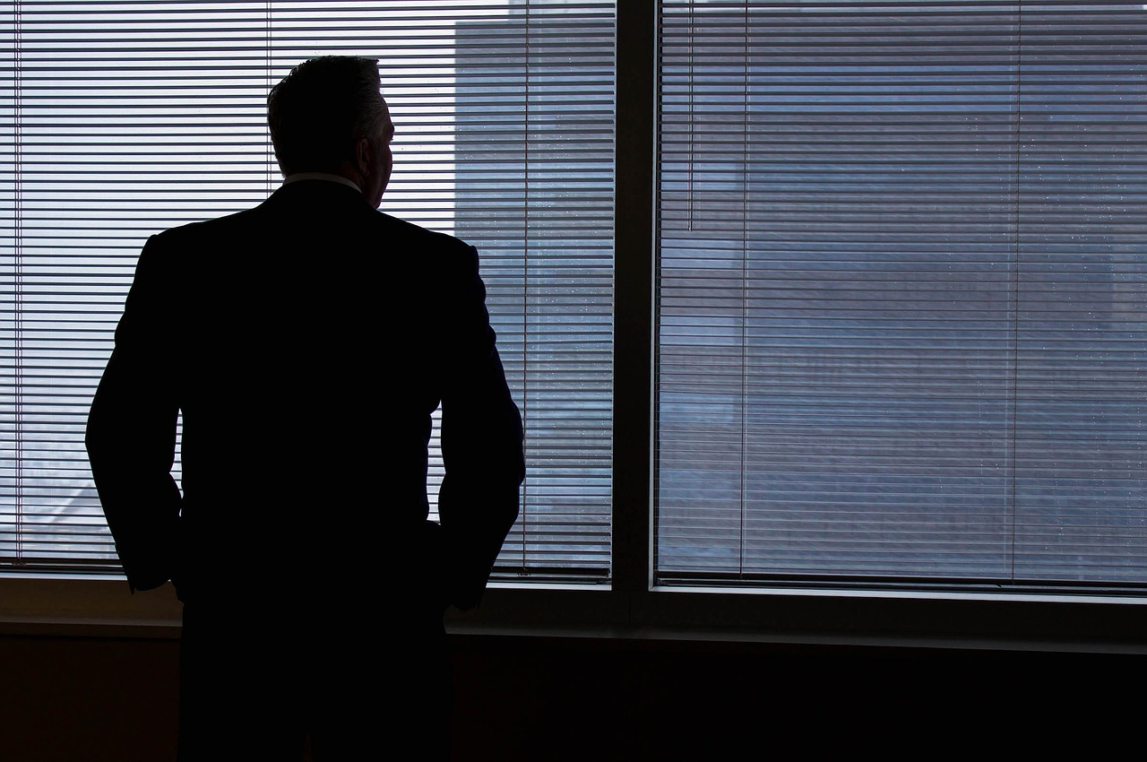 Silhouette of a businessman standing in front of window blinds in an office