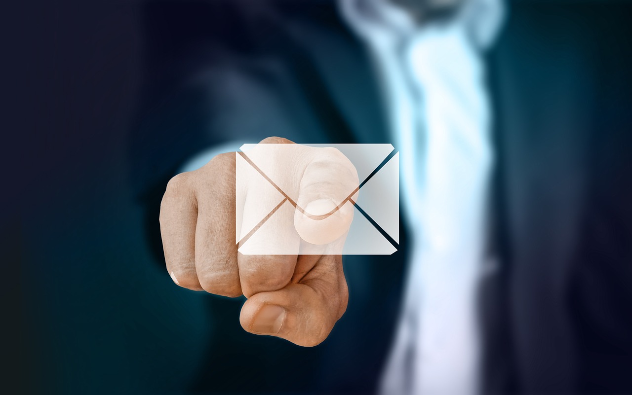 Businessman's hand touching a virtual screen with a white email envelope icon on it