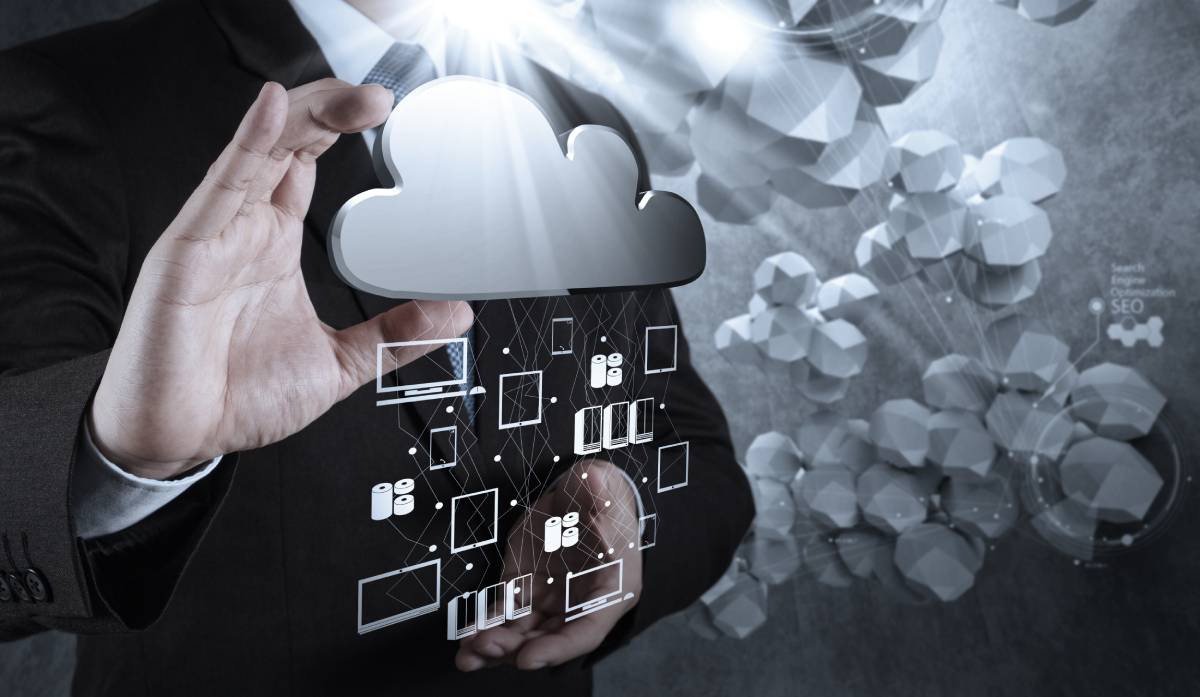 A businessman holding a silver cloud with servers and devices connected to it