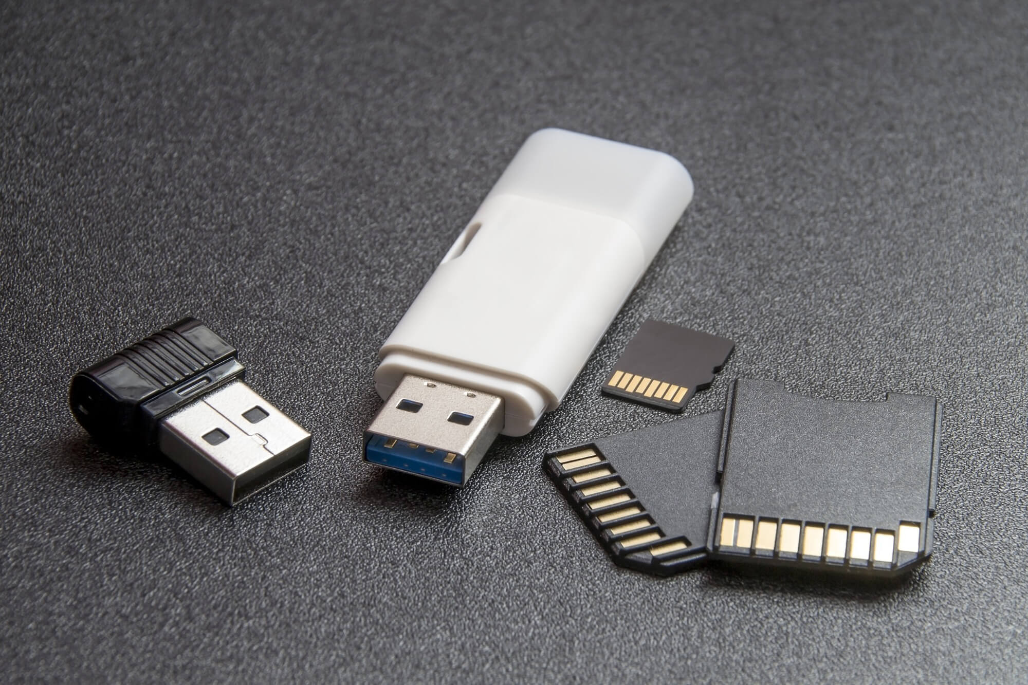 Wireless dongle, USB drive, micro SD chip, and 2 SD chips on a field of black