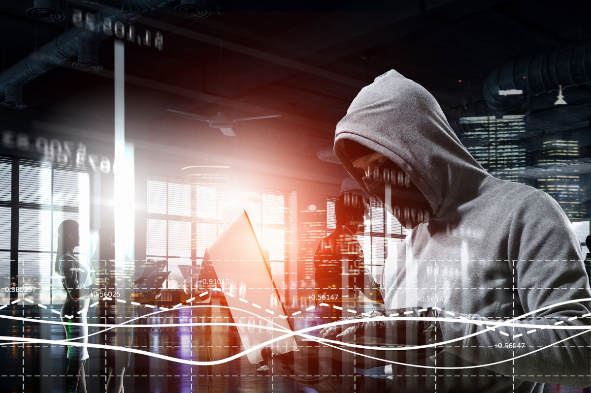 A hacker wearing a gray sweatshirt using a laptop