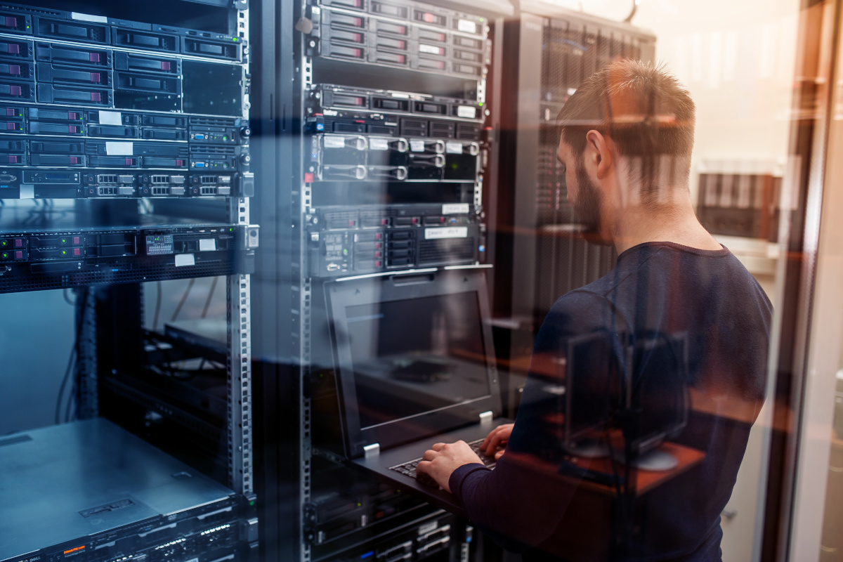 A person working on a computer connected to servers to implement data backup solutions