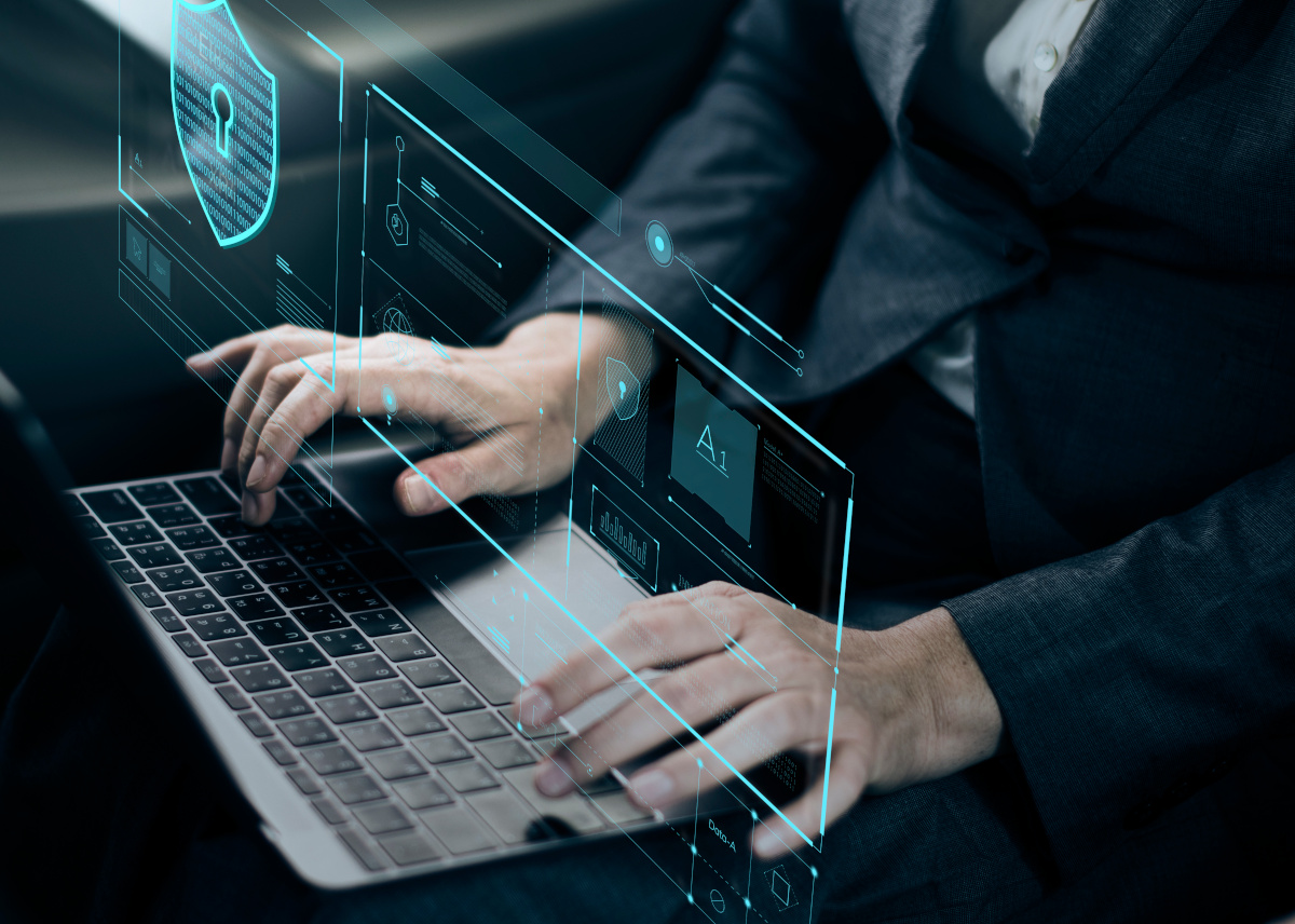 A businessman typing on a keyboard and there is a digital overlay over the keyboard with a sheild. Protection concept.