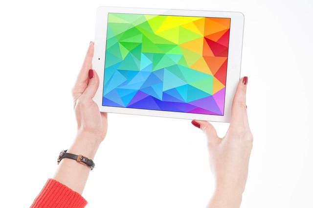 Woman's hands holding up an iPad displaying a colorful abstract image