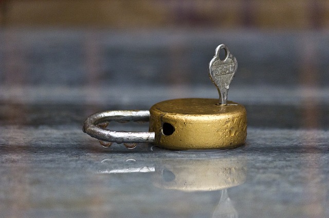 Gold-colored, unlocked circular padlock with a key inserted