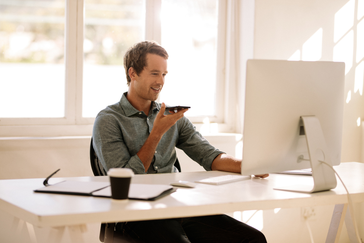 A man working from home at his desk talking on his smartphone 