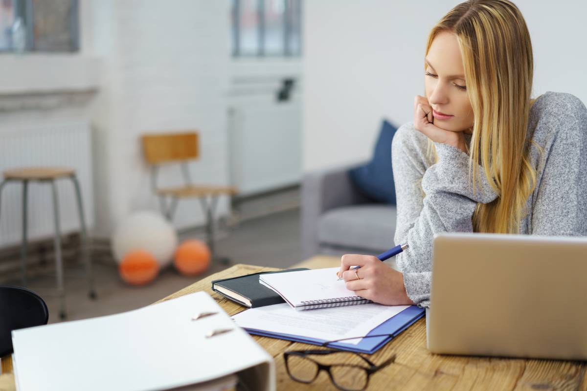 A blonde woman working remotely using a laptop