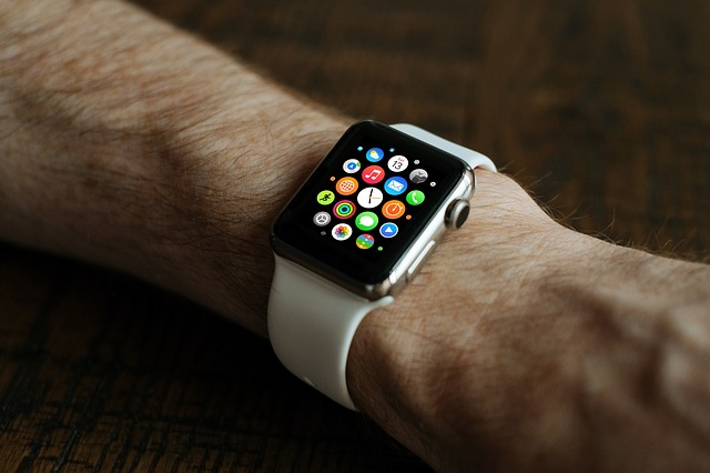 A man's forearm wearing a smart watch displaying numerous colorful icons