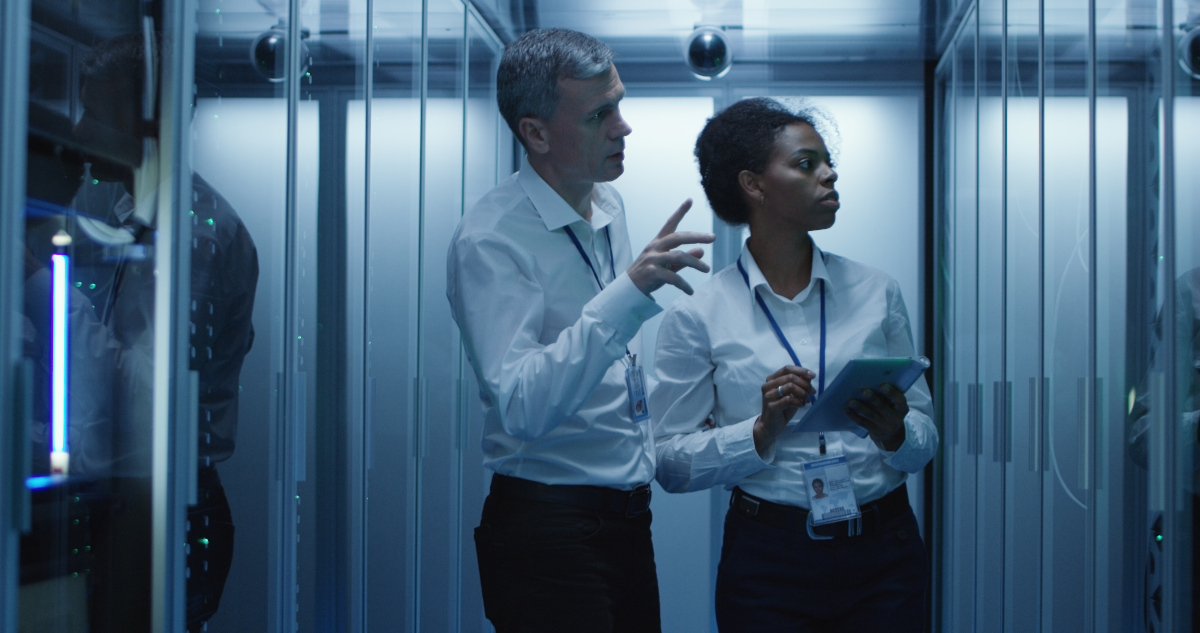 Man and woman IT technicians with tablet monitoring data in server room.