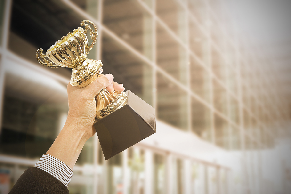 Close up of hand holding award trophy, success concept.