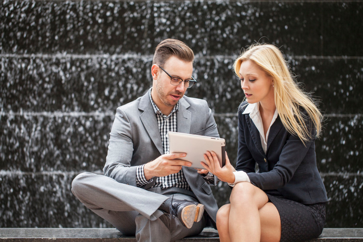 A man and woman using a tablet to work remotely