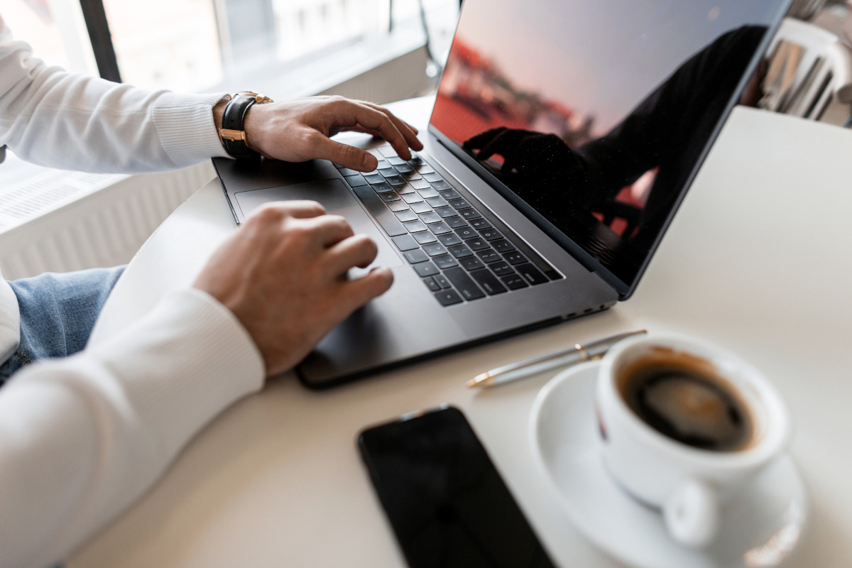 A person in a coffee shop working on their laptop