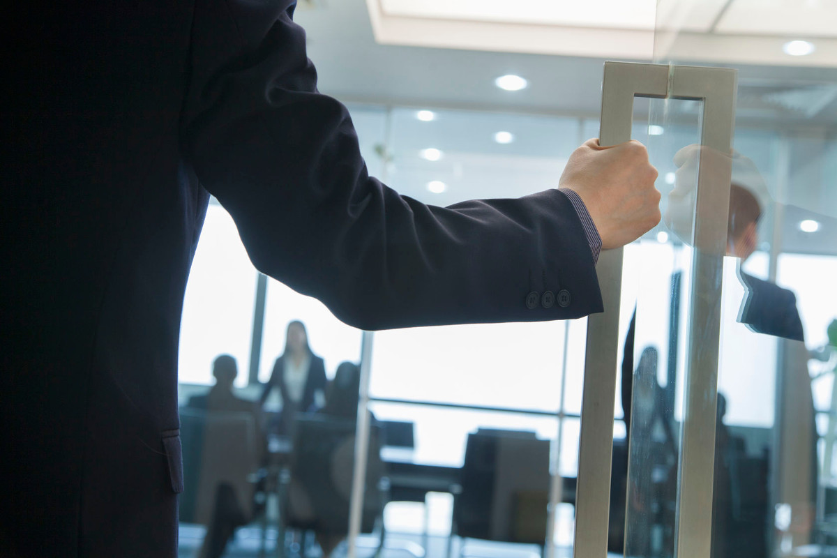 Businessman opening door and walking into an office full of people