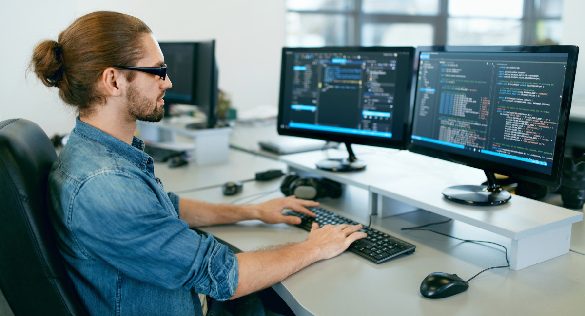 Businessman at Desk Working on a computer using two screens