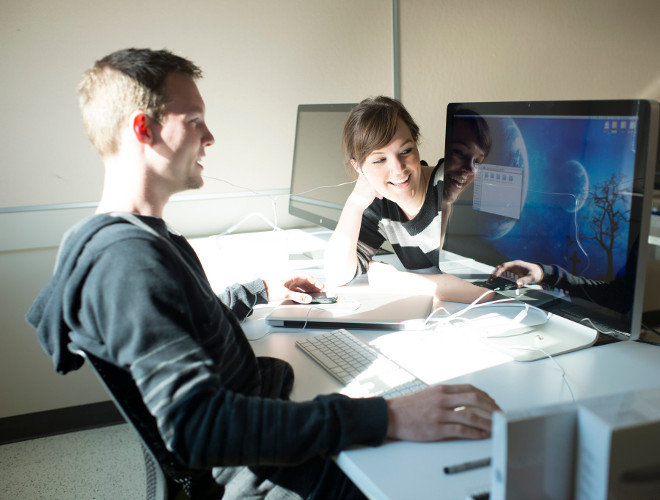 Smiling Man and Woman Looking at Computer Screen on Shared Work desk