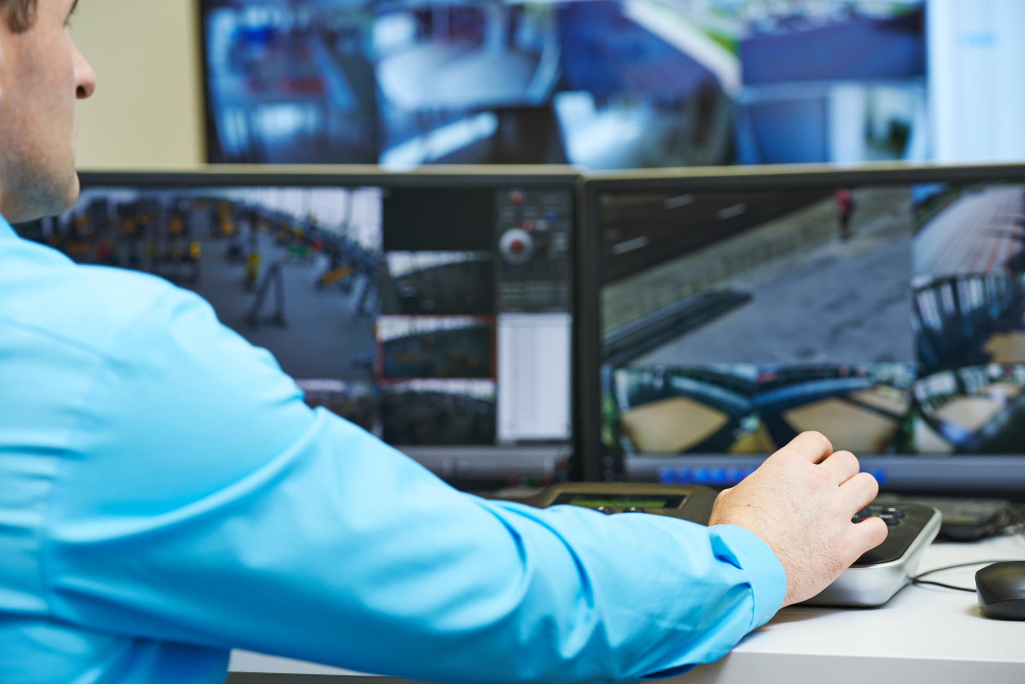 A man watching multiple monitors displaying surveillance camera footage